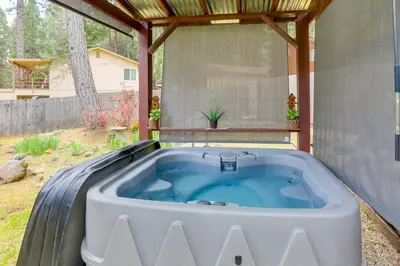 a hot tub in a backyard with a pergola at 1 Mi to Lake Hot Tub Haven in Pollock Pines! in Pollock Pines