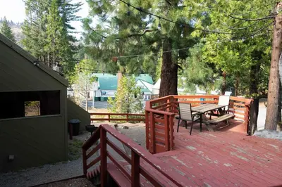 a wooden deck with a table and benches on it at Hawks Nest- Perfect Getaway in Shaver Lake in Shaver Lake