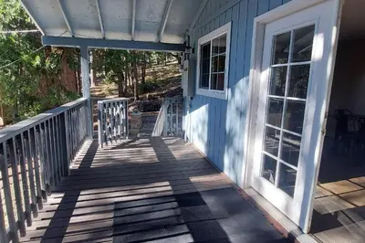 a front porch of a blue house with a door at 12 Mi to Apple Hill Family-Friendly Cabin Retreat in Pollock Pines