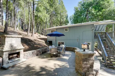 a patio with a fireplace and a table with an umbrella at 12 Mi to Apple Hill Family-Friendly Cabin Retreat in Pollock Pines