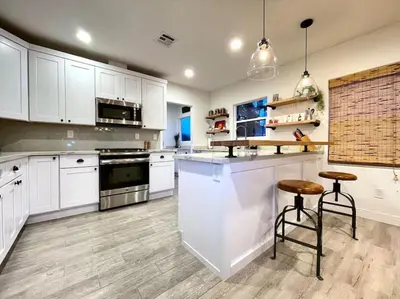 a kitchen with white cabinets and a counter with stools at King Bed-Private Yard-Driveway Parking in Sacramento