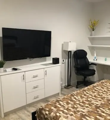 a bedroom with a flat screen tv and a chair at Villa Alamari Inn and Suites in Kerman