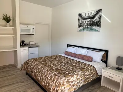 a small bedroom with a bed and a kitchen at Villa Alamari Inn and Suites in Kerman