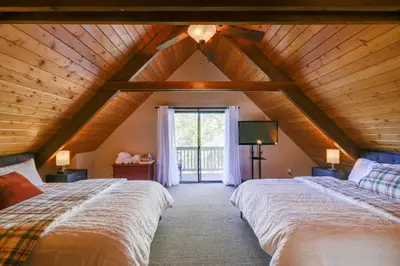 a attic bedroom with two beds and a window at Spacious Groveland Cabin with Wraparound Deck! in Groveland