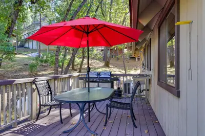 a table and chairs on a porch with a red umbrella at Spacious Groveland Cabin with Wraparound Deck! in Groveland