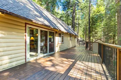 a wooden deck next to a house with trees at Jug Handle Hideaway in Arnold