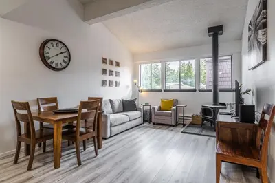 a living room with a table and a clock on the wall at Summit #256 - Top Floor Summit 1 Bedrm 1 Bathrm Condo Just steps too Little Eagle Lodge Sleeps 4 in Mammoth Lakes