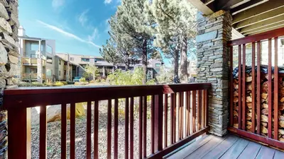 a balcony with a wooden railing and a stone wall at Summit #105 condo in Mammoth Lakes