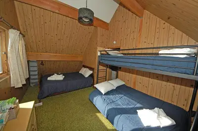 two beds in a room with wooden walls at 1116 Golden Bear home in South Lake Tahoe