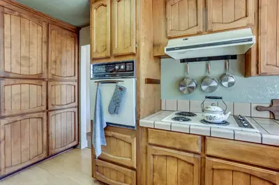 a kitchen with wooden cabinets and a stove top oven at Pet-Friendly Escape with Game Room and Fire Pit! in North Fork