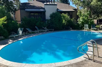 a large blue swimming pool with chairs in front of a house at Sherwin Villas 12 B in Mammoth Lakes