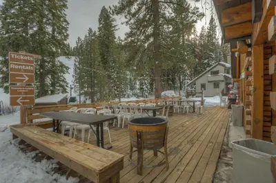 a wooden deck with tables and chairs in the snow at Granlibakken Gem - Unit 71 in Tahoe City