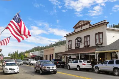 a town street with cars and an american flag at Foothill Acres in Midpines