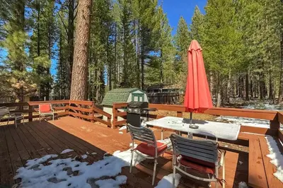 a wooden deck with a table and a red umbrella at 1763 Saponi Street home in South Lake Tahoe