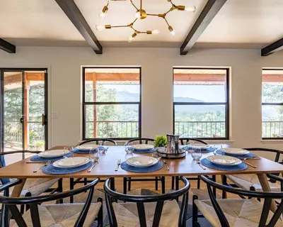 a dining room with a table and chairs and windows at Secluded Mtn Top Family Haven w/Views Spa & Arcade in Three Rivers
