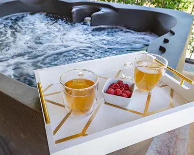 two glasses of tea and berries on a tray next to a hot tub at Secluded Mtn Top Family Haven w/Views Spa & Arcade in Three Rivers