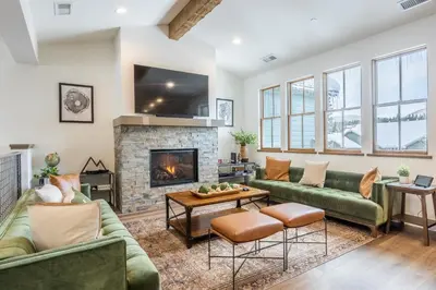 a living room with green couches and a fireplace at Newly Built Updated 3 Bed 2 and a half bath Creekhouse at Snowcrk Resort 1463 Amazing Mountain Views in Mammoth Lakes