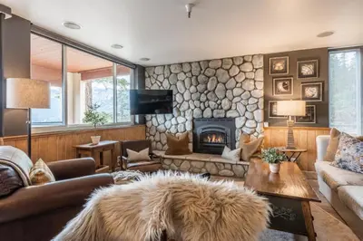 a living room with a stone wall with a fireplace at Bridges 112 in Mammoth Lakes