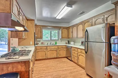 a kitchen with wooden cabinets and a stainless steel refrigerator at 7 Mi to Yosemite Natl Park Riverfront Getaway! in Groveland
