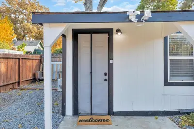 a small white shed with a door in a yard at A Cottage - Walk to UC Davis & Shriners in Sacramento