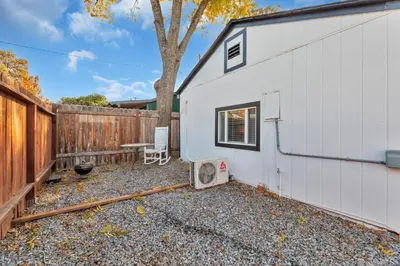 a backyard with a white building and a fence at A Cottage - Walk to UC Davis & Shriners in Sacramento
