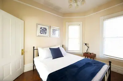 a bedroom with a blue and white bed and two windows at A+ 2 BR Victorian Home away from Home in Sacramento