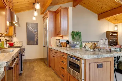 a kitchen with wooden cabinets and granite counter tops at Hot Tub and Scenic Views Luxury Twain Harte Cabin! in Twain Harte