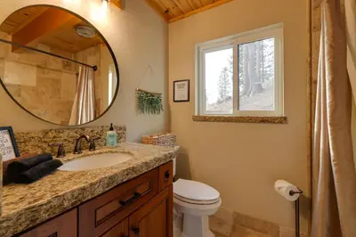 a bathroom with a sink and a toilet and a mirror at Hot Tub and Scenic Views Luxury Twain Harte Cabin! in Twain Harte