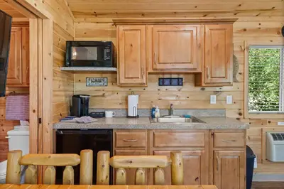 a kitchen with wooden cabinets and a sink and a microwave at Adorable little cabin #21 in Kernville
