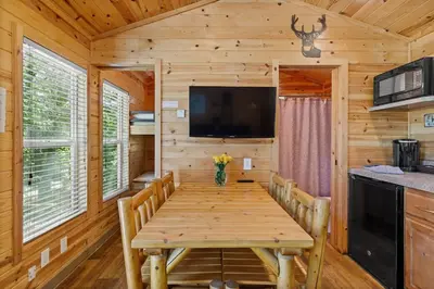 a dining room with a wooden table and a flat screen tv at Deluxe little cabin 2 min stroll to Kern River in Kernville