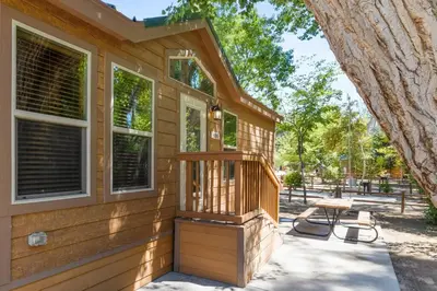 a wooden house with a porch and a picnic table at Deluxe little cabin 2 min stroll to Kern River in Kernville