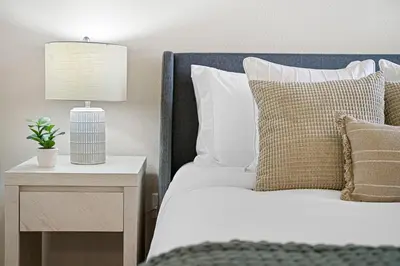 a bed with a nightstand with a lamp on it at Designer Apt w Jacuzzi Walk To Casino & iMax in Sparks