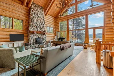 a living room with a stone fireplace in a log cabin at Willow Cove Log Cabin in Bass Lake