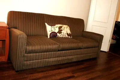 a brown couch with a pillow on it in a room at Chateau Sunnyside in Fresno