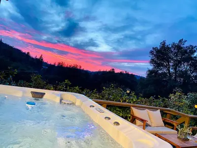 a hot tub with a sunset in the background at Cozy Cabin Near Yosemite & Bass lake, Breathtaking Views & Private Hot Tub, BBQ, Nature Getaway in Oakhurst