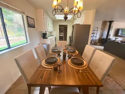 a wooden dining room table with chairs and a kitchen at Cozy Cabin Near Yosemite & Bass lake, Breathtaking Views & Private Hot Tub, BBQ, Nature Getaway in Oakhurst