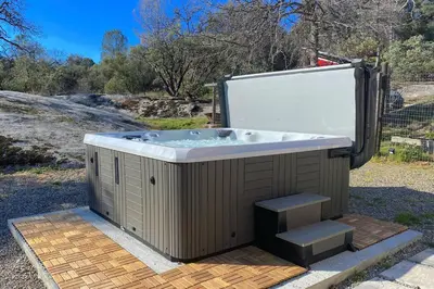 a hot tub sitting on top of a wooden deck at Relax at Yosemite, Cozy House with King Bed, Private Hot Tub & Fast Wi-Fi, Near town in Oakhurst