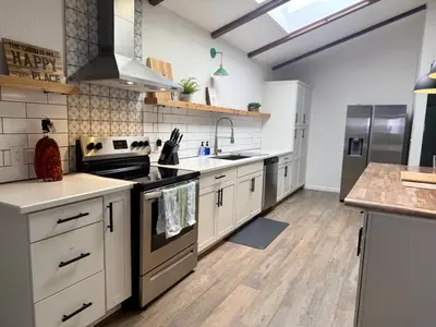 a kitchen with stainless steel appliances and wooden floors at The Happy Cabin w/ hot tub in Oakhurst