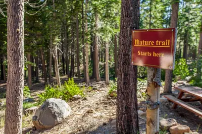 a sign for a nature trail with a bench in the woods at Silver Strike Serenity in Truckee