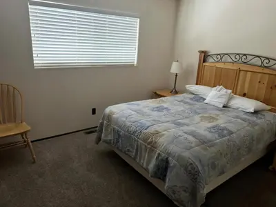 a bedroom with a bed and a window and a chair at Close To Heaven With Hot Tub, Wet Bar & Game Room in South Lake Tahoe