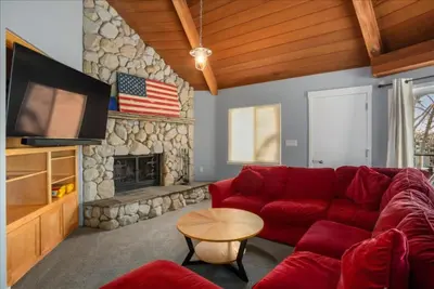 a living room with a red couch and a stone fireplace at Private Beach, Close To Everything in South Lake Tahoe