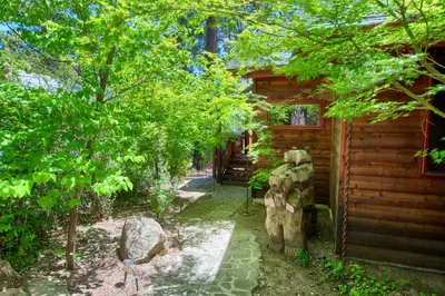a garden outside a log cabin with a statue next to it at Willow Cove Lodge- 5 bedrooms with a hot tub in Bass Lake