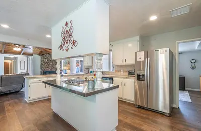 a kitchen with white cabinets and a stainless steel refrigerator at Starry Pines- Pet friendly/spa/affordable in Oakhurst