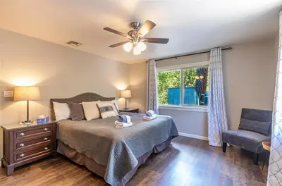 a bedroom with a bed with a ceiling fan and a chair at Starry Pines- Pet friendly/spa/affordable in Oakhurst