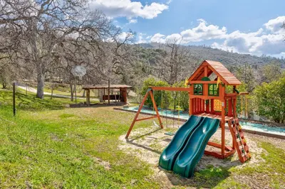 a playground with a slide and a house at Selah Cabin- Dog Friendly/BBQ/Level 2 EV Charger in Oakhurst