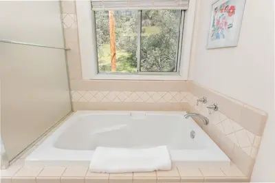 a white bath tub in a bathroom with a window at Selah Cabin- Dog Friendly/BBQ/Level 2 EV Charger in Oakhurst