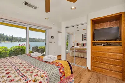 a bedroom with a bed with a large window and a television at Eagles Nest at Bass Lake near Yosemite with Boat Dock in Bass Lake