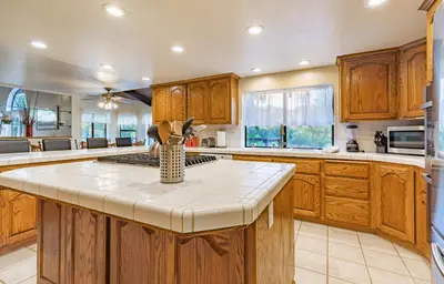 a kitchen with wooden cabinets and a white counter top at River View Retreat Sleeps 16/ hot tub/basketball court in Oakhurst