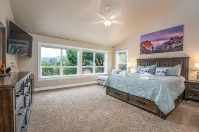 a bedroom with a bed and a tv and windows at Yosemite Adventure House with Pool-hot tub-game room in Oakhurst