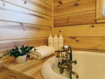 a bathroom with a sink and a wooden wall at Log Cabin w/ pool, spa, game room, sleeps 20 in Coarsegold